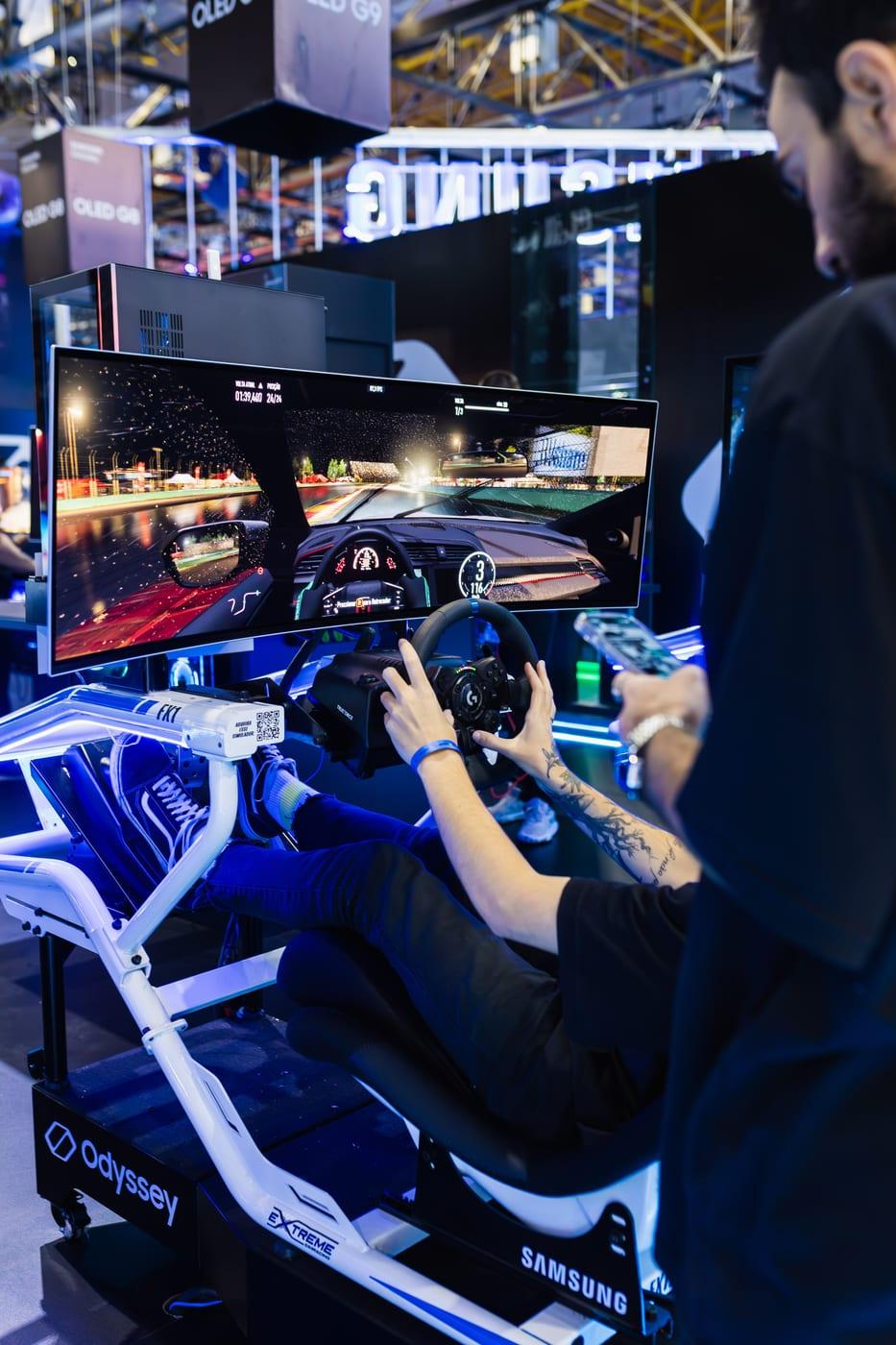 A player at a racing-simulator rig, hands on the steering wheel in front of an ultrawide monitor